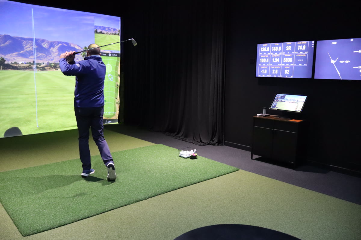 Golfer in action with full simulator setup visible